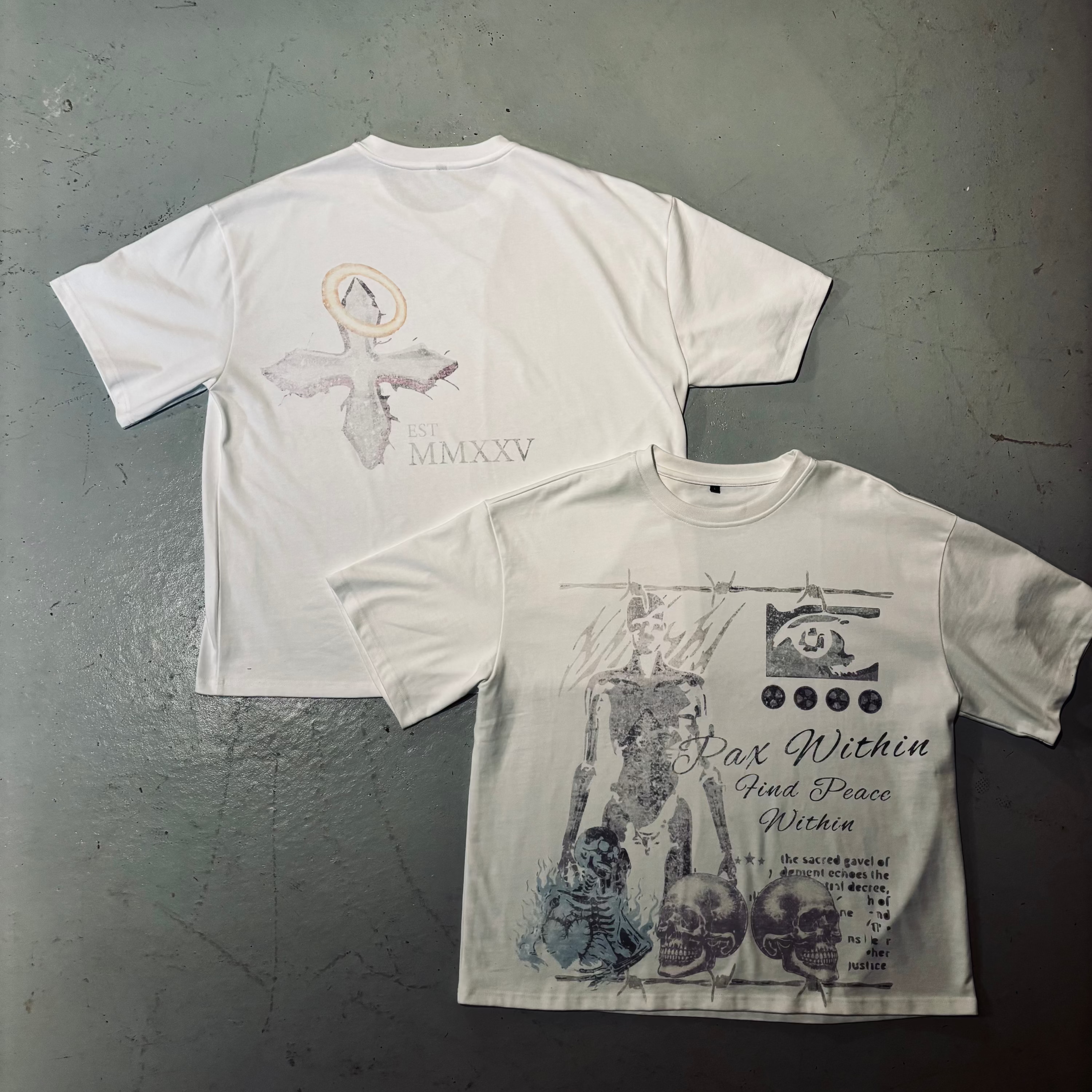 Two white t-shirts with graphic designs on a textured gray surface