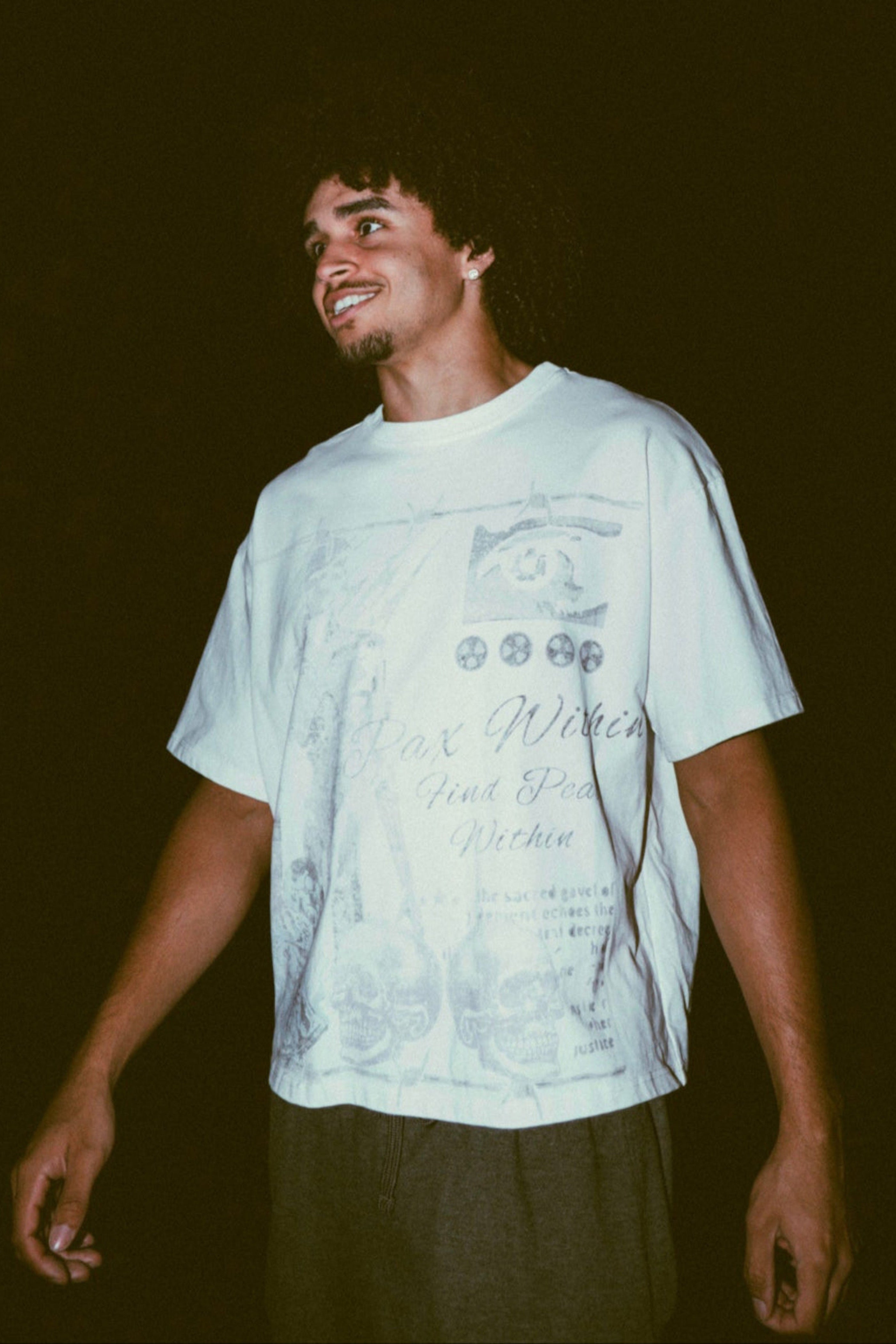 Person wearing a white t-shirt with text and graphics against a dark background